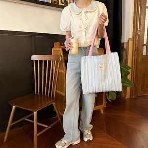 Borsa tote in tela a righe verticali con tracolle rosa e etichetta indossata da modella