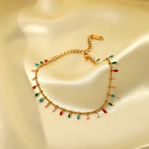 Detail of gold stainless steel bracelet with colorful water drop charms on silk background