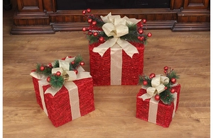 Detailed view of red and gold Christmas LED gift boxes with pine needles and berries