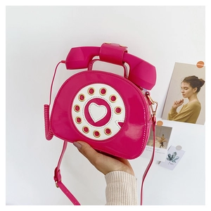 Detailed macro view of the patent leather telephone shaped crossbody bag in bright pink