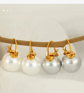 Élégantes boucles d'oreilles perles blanches et gris argenté sur une branche rustique