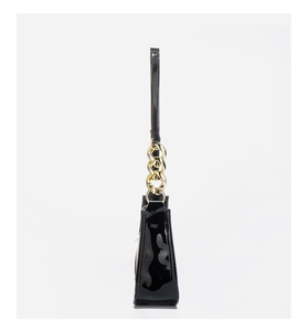 Detail view of glossy black faux leather shoulder bag featuring gold chain strap link