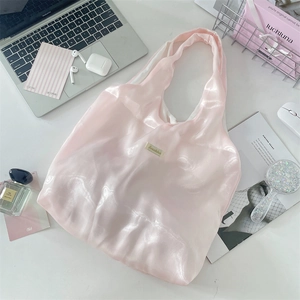 Detail of pink satin tote bag on a desk with elegant lifestyle accessories and soft sheen