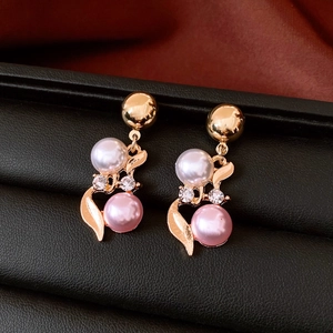 Close-up of French vintage gold earrings with pearls and rhinestones on black leather