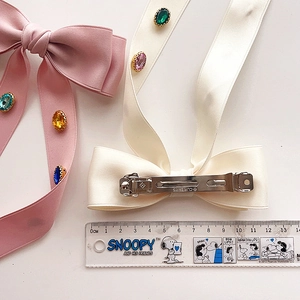 Detailed back view of a satin bow hair clip with silver metal spring fastener and colorful gems