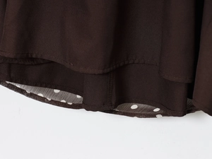 Detail view showing stitching and layered hem of a dark coffee polka dot chiffon blouse