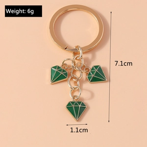 Macro detail of gold keychain with three green diamond-shaped pendants and size labels