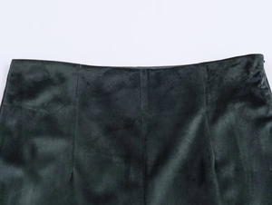Gros plan sur la texture velours vert foncé et la couture de la taille du pantalon