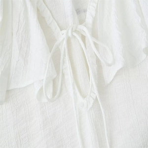Dettaglio ravvicinato del tessuto plissettato bianco e dello scollo con coulisse