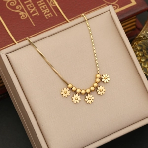 Elegant beaded gold flower necklace displayed in a beige jewelry box with vintage books