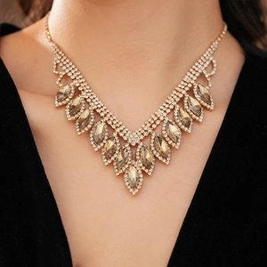 Close-up of elegant V-shaped gold necklace with amber stones and rhinestones on a model