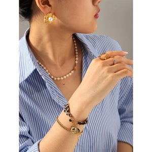 Detailed view of 18k gold plated twisted earrings and layered jewelry set on a model