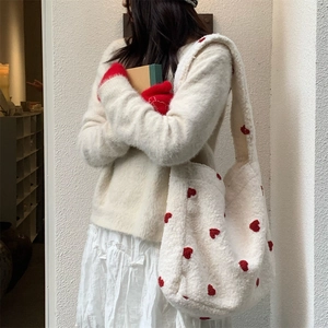Detailed shot of white plush tote bag with red heart embroidery on soft faux fur fabric