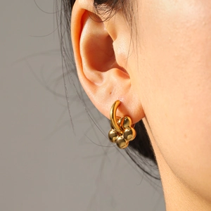 Macro side view of model wearing gold 18k stainless steel floral hoop earrings
