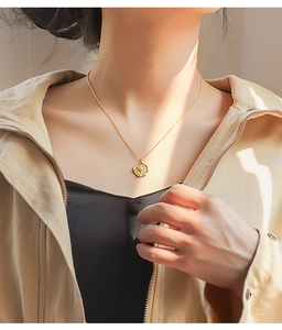 Detail of vintage gold star-stamped pendant necklace on model with warm lighting