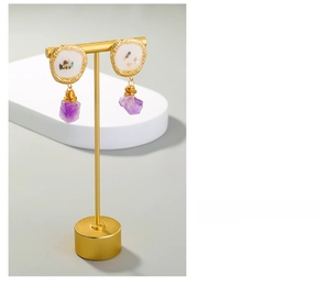 Detail view of purple raw amethyst stone pendant earrings with golden textured edges