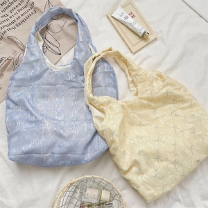 Détail des sacs cabas matelassés avec imprimés nœuds délicats dans des tons doux