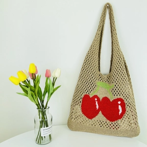Detailed close-up of beige hollow knit tote bag featuring red cherry crochet pattern