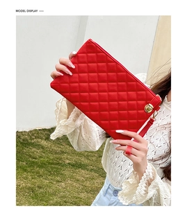 Detail of red quilted clutch bag featuring a metallic lock and high-quality PU leather