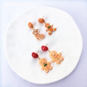 Macro view of gingerbread man and Christmas stocking earrings on a white tray