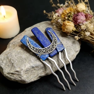 Detailed view of silver crescent moon hair pins with blue lapis lazuli on grey rock