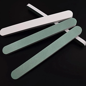Close-up of four double-sided nail polishing files with green and white grit surfaces