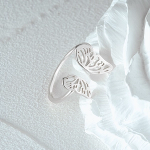 Macro shot of silver butterfly wing open ring resting on a delicate white petal