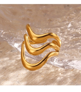 Detailed close-up of a multi-layer wave-shaped gold-plated ring on a glass tray