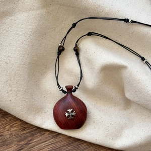 Macro shot of wooden heart pendant with metal cross on textured linen background