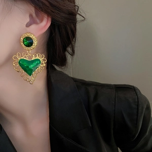 French vintage gold and emerald heart drop earrings worn by a model in profile