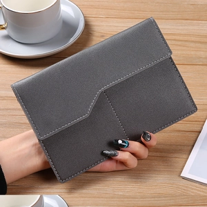 Close-up of gray faux leather envelope clutch with white stitching on wooden table