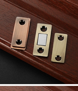 Detail of red bronze magnetic cabinet door catch hardware on dark wood texture