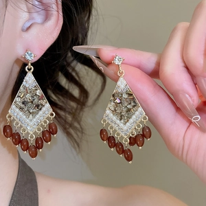 Detail view of rhombic earrings with crystal fringes and pearls on a gold frame