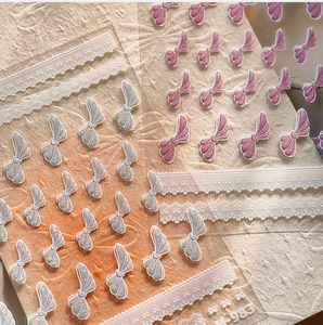 Detailed view of 3D embossed nail art stickers with pink bows and silver glitter lace