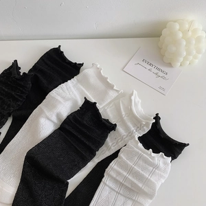 Detailed view of sheer mesh texture and ruffled lace edges on black and white socks