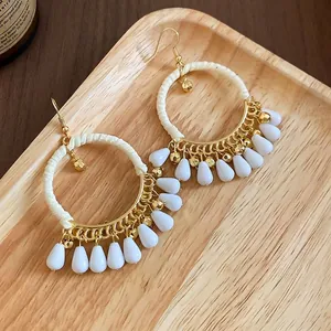 Bohemian drop earrings with woven rope circles and white waterdrop beads on a tray