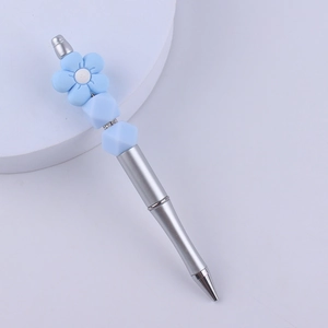 Detail of silver beadable pen featuring blue floral silicone bead and faceted accents