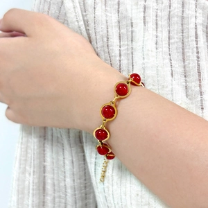 Elegant gold bracelet with red round stones shown on wrist for a minimalist style