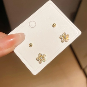 Detailed view of silver needle flower stud earring set with zircons and gold spherical studs