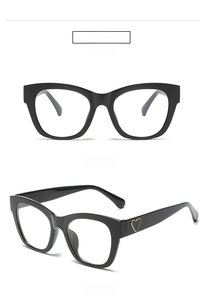Close-up detail of stylish black square frame glasses featuring gold heart temple accents