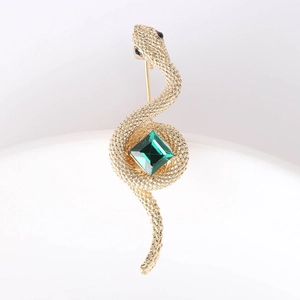 Close-up of golden cobra brooch with green gemstone inlay and intricate snake scale detail