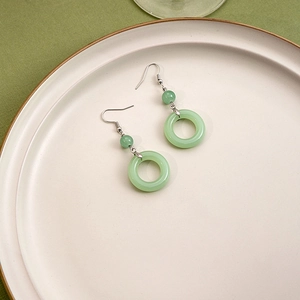 Detail of light green jade drop earrings with silver hooks in a ceramic dish