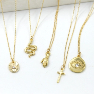 Detail shot of five retro bohemian gold necklaces featuring snake and evil eye pendants