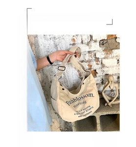 Détail du sac cabas en toile crème montrant la texture du tissu et l'imprimé lettre