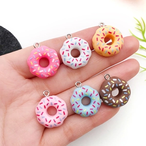 Handheld set of six colorful resin donut pendants with sprinkles for DIY jewelry making