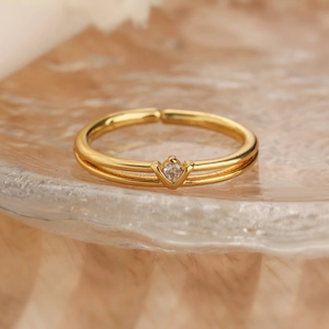 Close-up of 18K gold plated double band ring with sparkling zircon on glass base