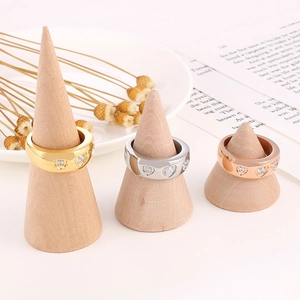Dettaglio di anelli a cuore in oro, argento e oro rosa su supporti in legno naturale
