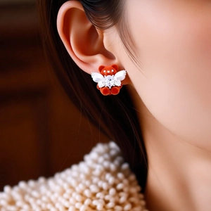 Detail view of a flocked brown bear earring with white wings and sparkling crystals