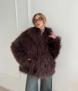 Detail of dark brown faux fox fur coat texture on model with plush fluffy finish