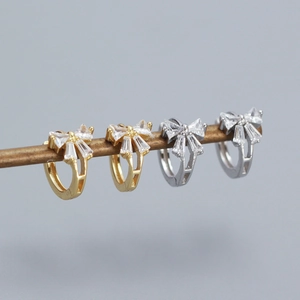 Close-up of elegant bow stud earrings in gold and silver finish with zircon stones